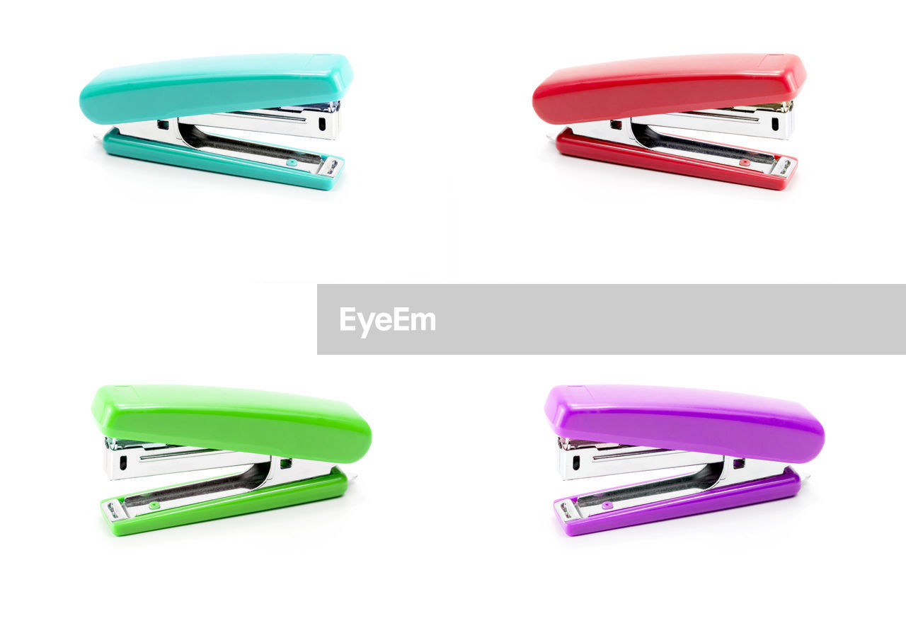 Multi colored staplers on white background