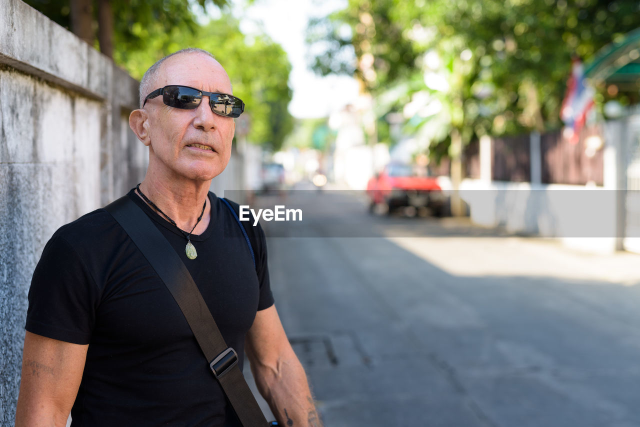 PORTRAIT OF MAN WEARING SUNGLASSES STANDING AT STREET
