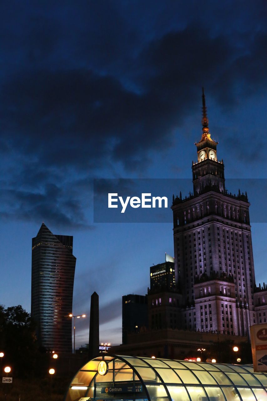 Palace of culture and science and modern building against sky at dusk