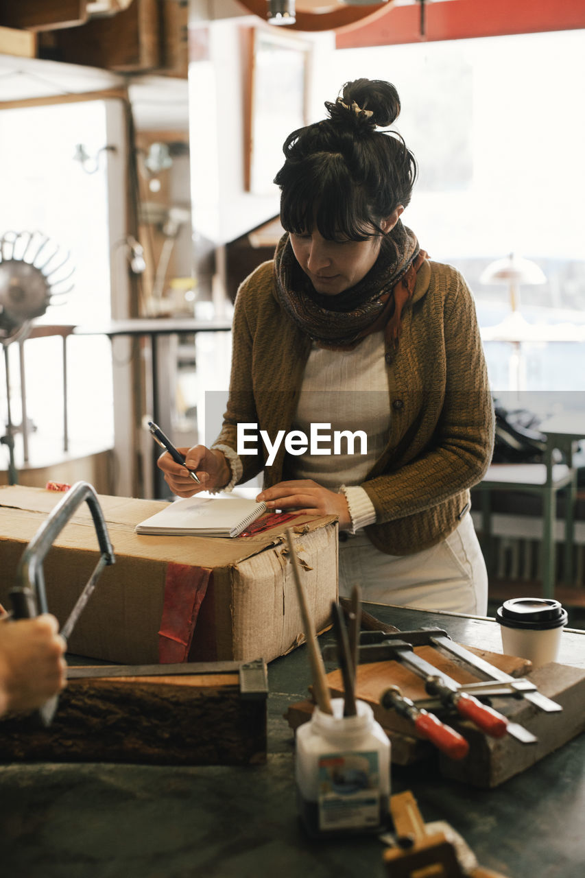 Female customer writing in diary at repair shop