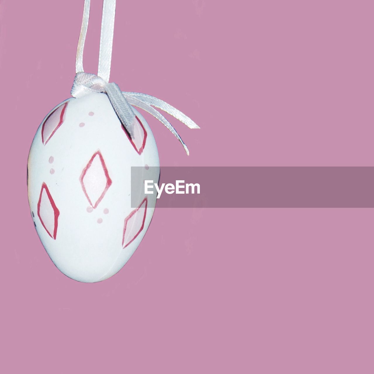 Easter egg hanging against pink wall