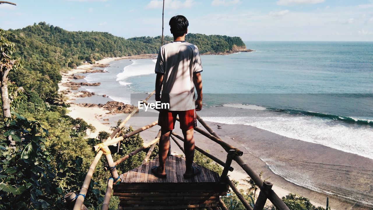 Rear view of man looking at sea while standing on observation point
