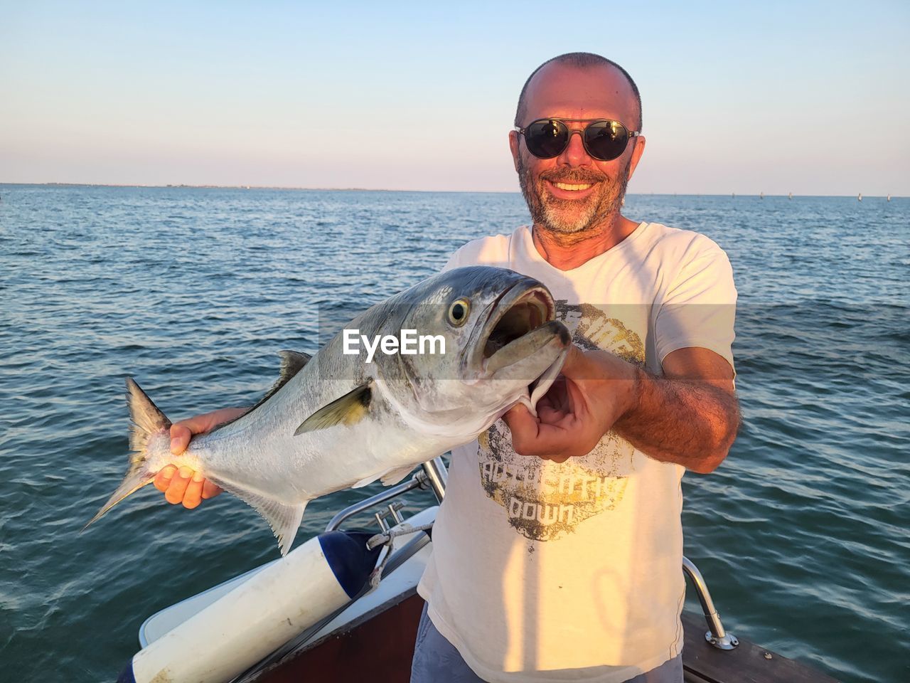 water, sea, animal, fish, animal themes, nature, one person, smiling, fishing, adult, men, big-game fishing, one animal, catch of fish, sunglasses, sky, looking at camera, portrait, animal wildlife, happiness, fashion, leisure activity, glasses, vacation, wildlife, recreation, seafood, trip, activity, emotion, sea life, holding, transportation, nautical vessel, outdoors, holiday, marine, food, front view, travel, horizon over water, horizon, day, food and drink, sunlight, achievement, waist up, trophy, clear sky, cheerful, sunny, success, fisherman, rod, award, freshness, mature adult, fishing industry