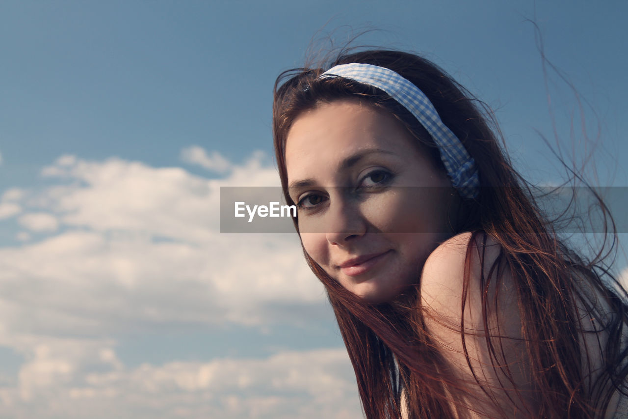 Portrait of smiling woman against sky