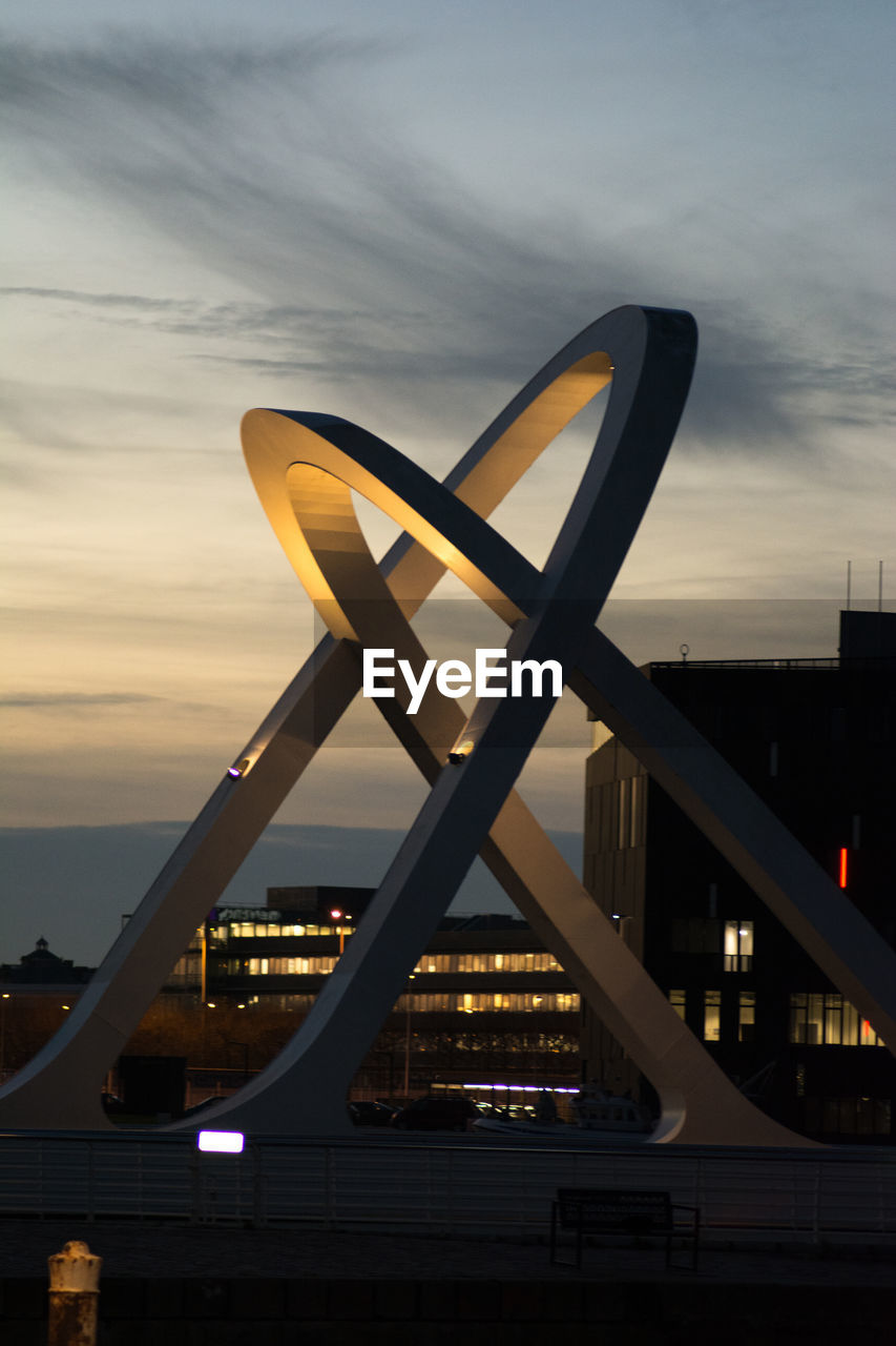 Modern bridge against sky in city at dusk