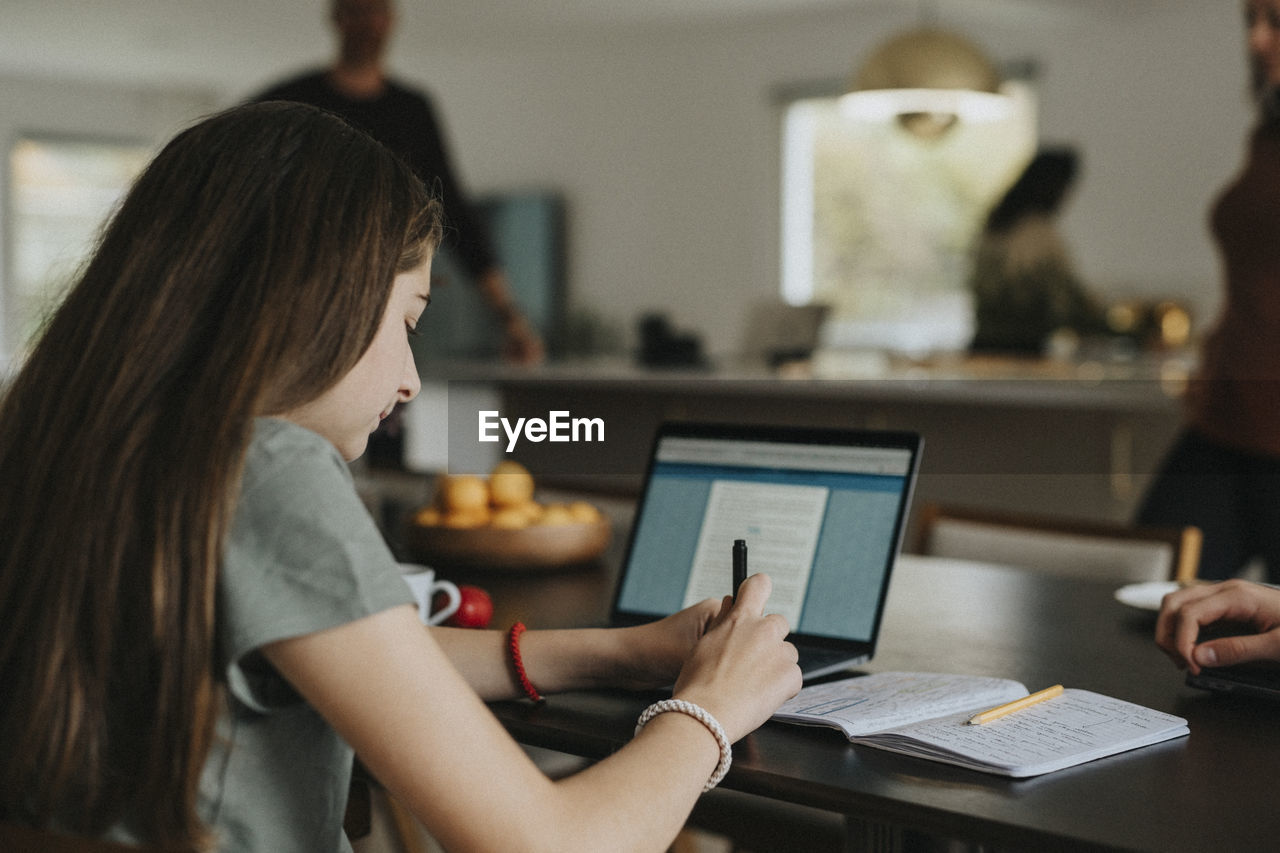 Pre-adolescent girl using laptop while sitting at home