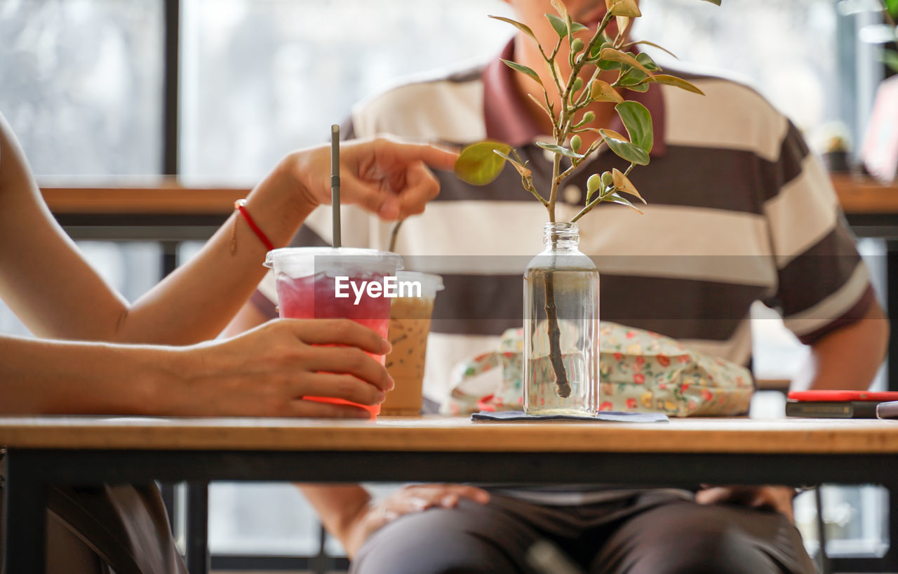 Midsection of woman holding drink at restaurant