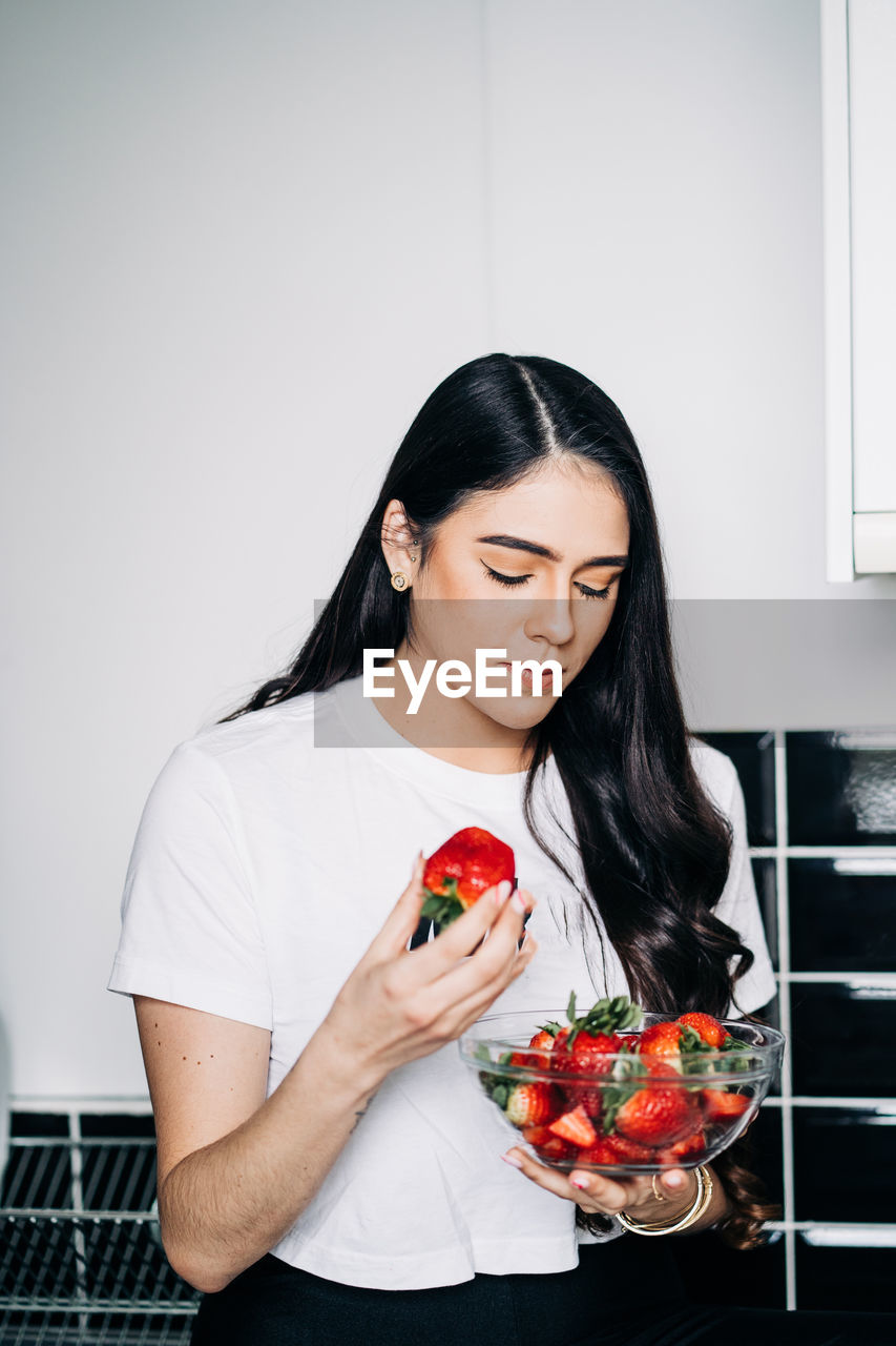 Young woman holding bowl of strawberries