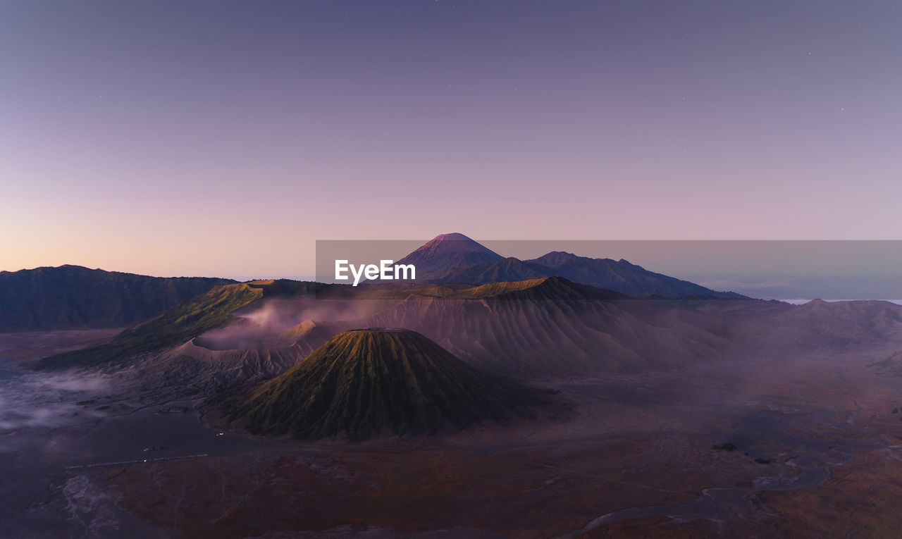 Scenic view of volcanoes against clear sky during sunset