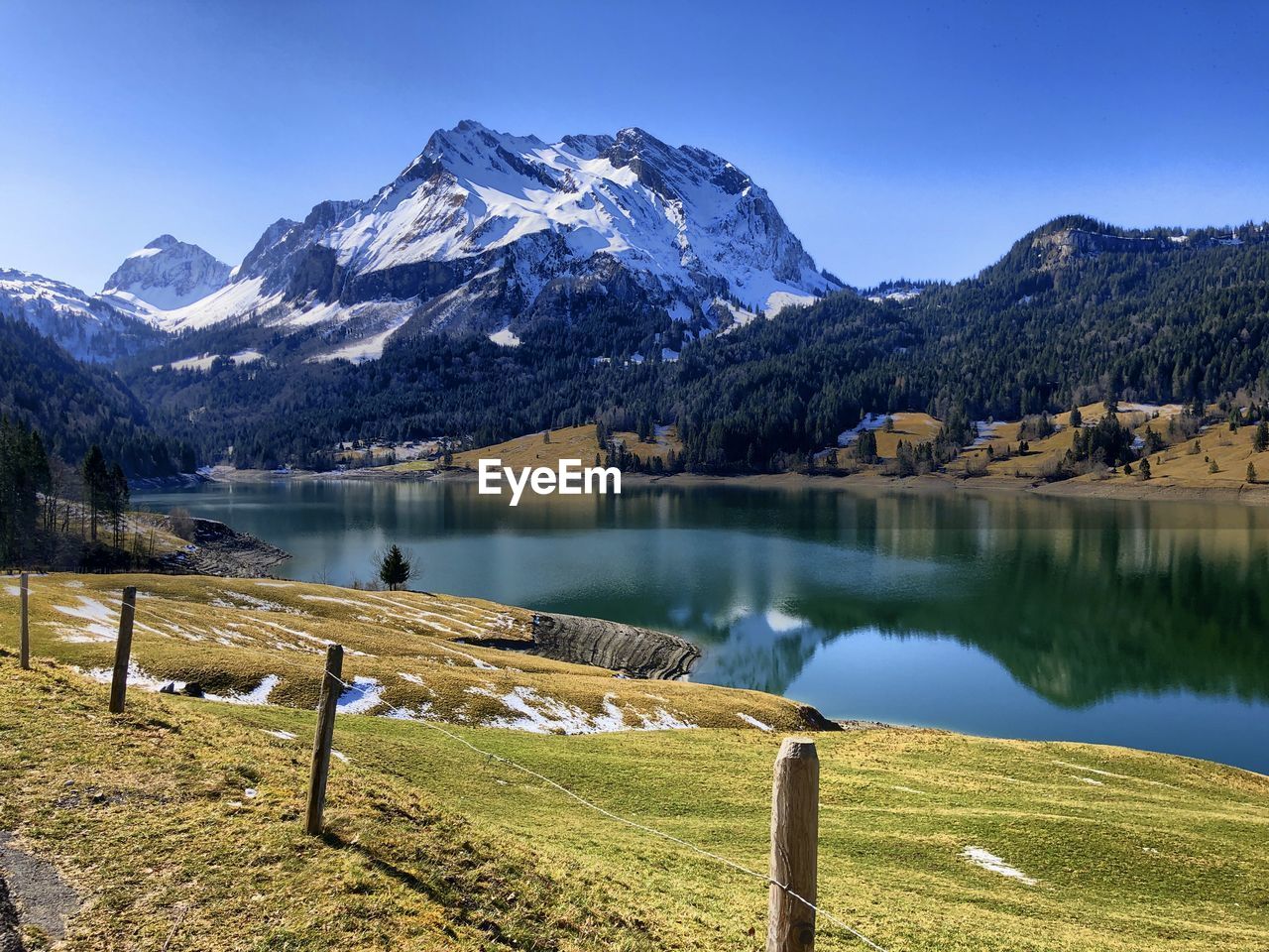 Scenic view of lake by snowcapped mountains against sky