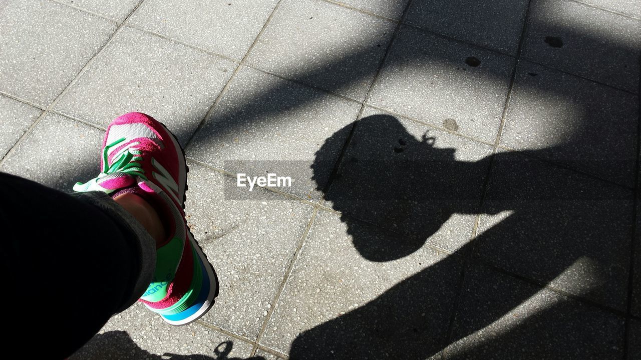 LOW SECTION OF WOMAN STANDING ON TILED FLOOR