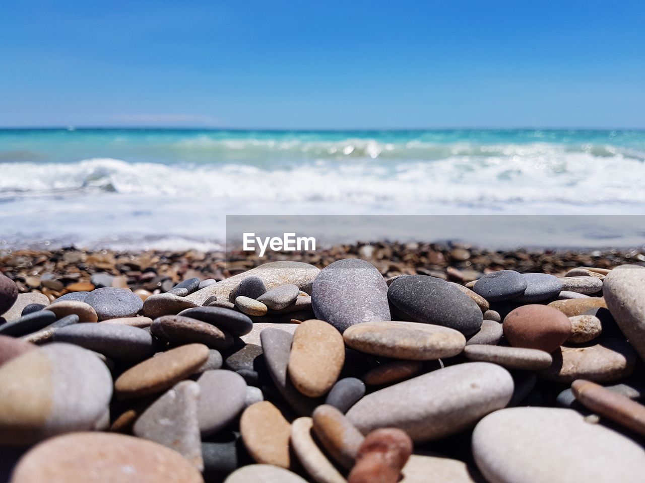 Close-up of pebbles on beach against blue sky