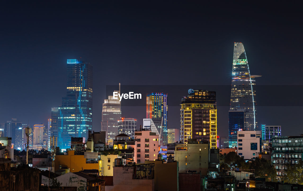 ILLUMINATED MODERN BUILDINGS AGAINST SKY AT NIGHT