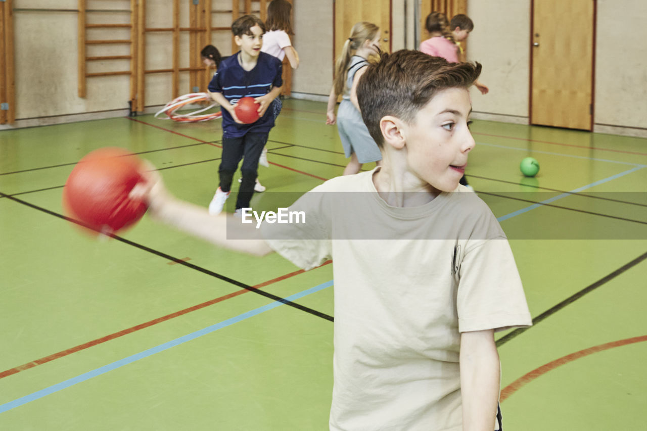 Boy throwing ball during pe class in school gym