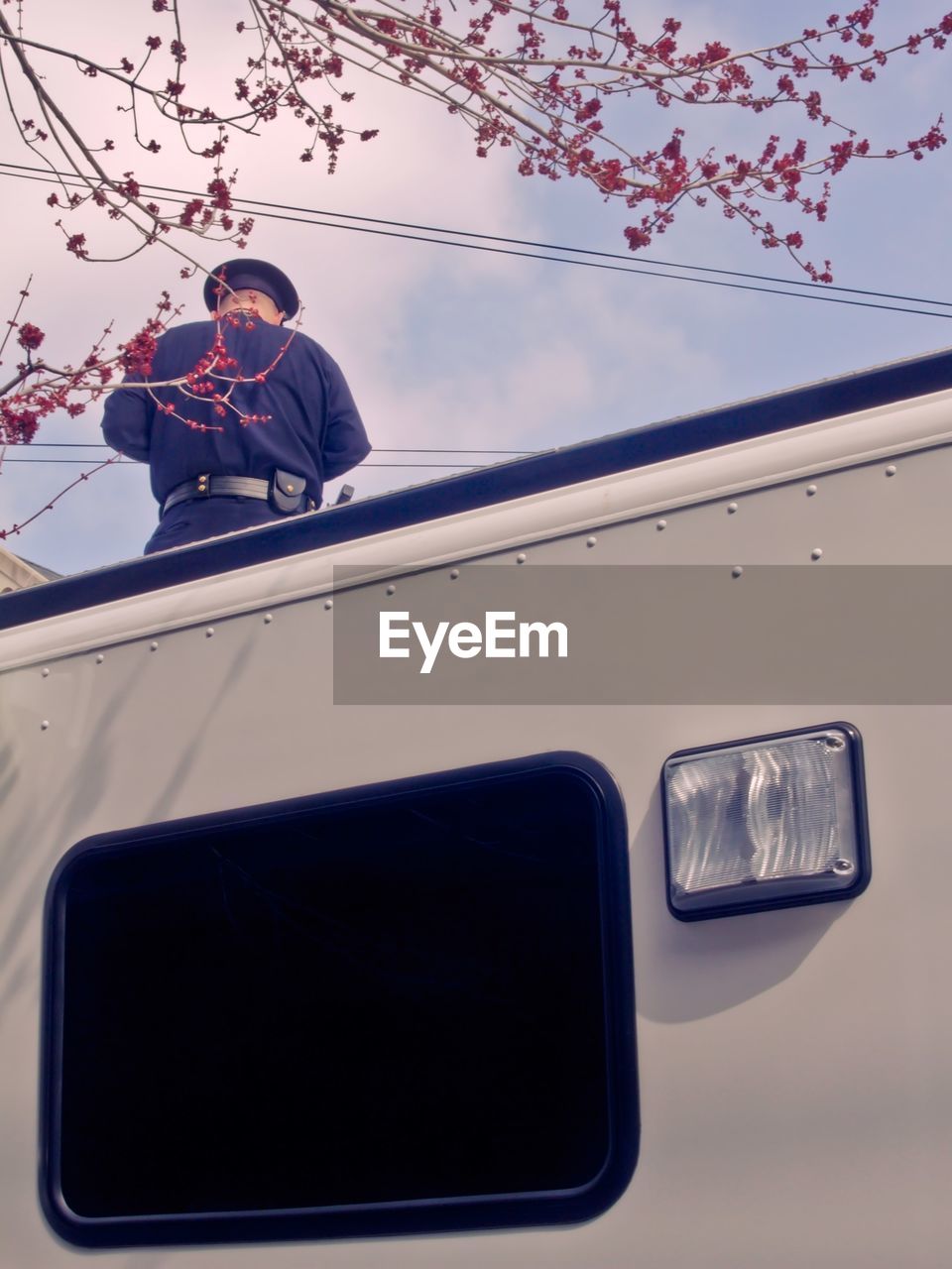 Low angle view of man standing on car against sky