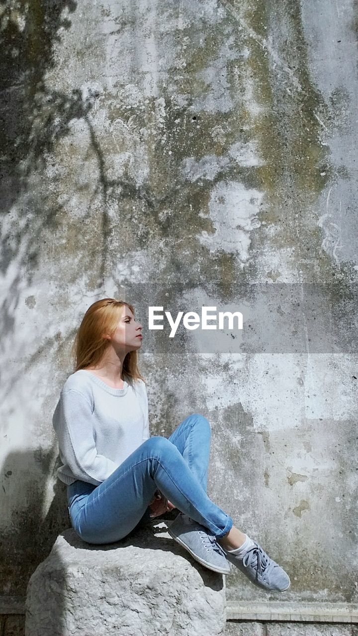 FULL LENGTH OF WOMAN SITTING ON FLOOR