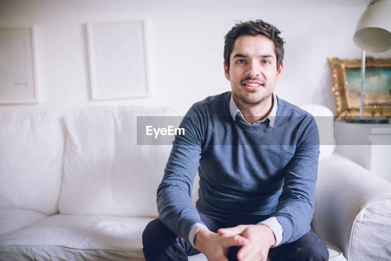 Portrait of young man sitting on sofa at home