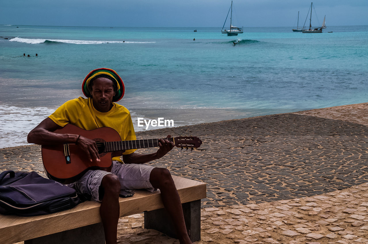 MAN SITTING ON THE BEACH