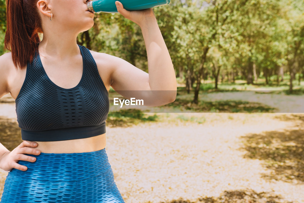 Woman drinking water from bottle in park