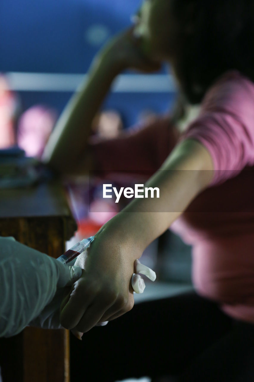 High angle view of doctor injecting syringe on woman hand