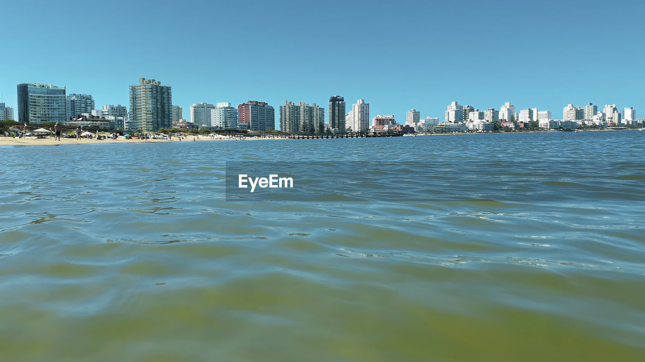 SEA BY BUILDINGS AGAINST SKY IN CITY