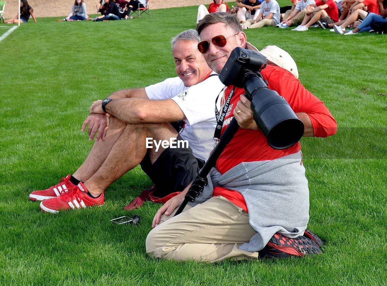 TWO MEN WITH UMBRELLA ON GRASSLAND