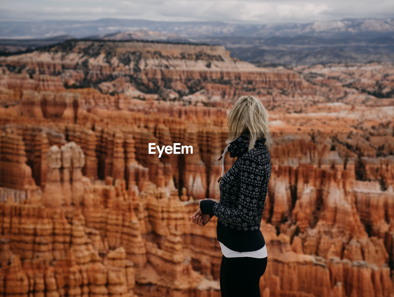 Woman looking away while standing against rock formation