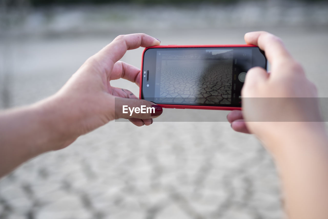 Close up of hands taking a photo with cellphone of landscape.