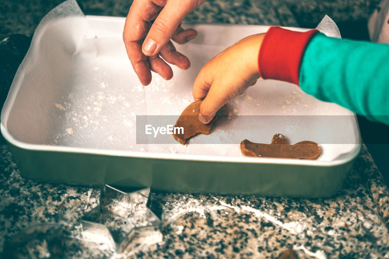 Moment unfolds in kitchen as a mom and son engage in tradition of preparing christmas gingerbread.