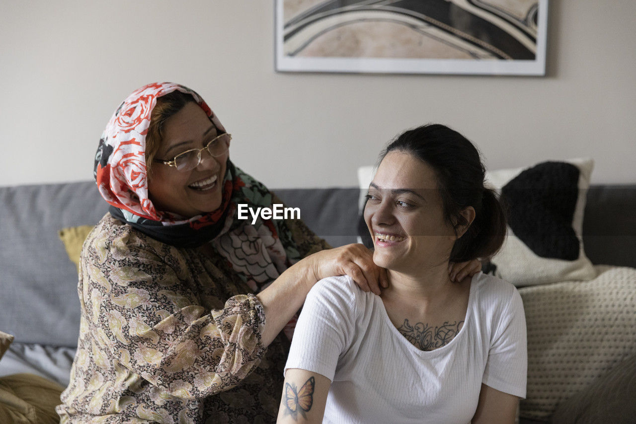 Happy mother talking and massaging to daughter with paraplegia at home