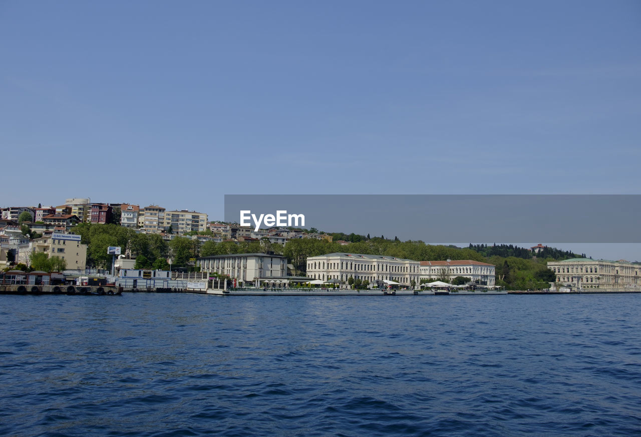 Buildings by sea against clear sky