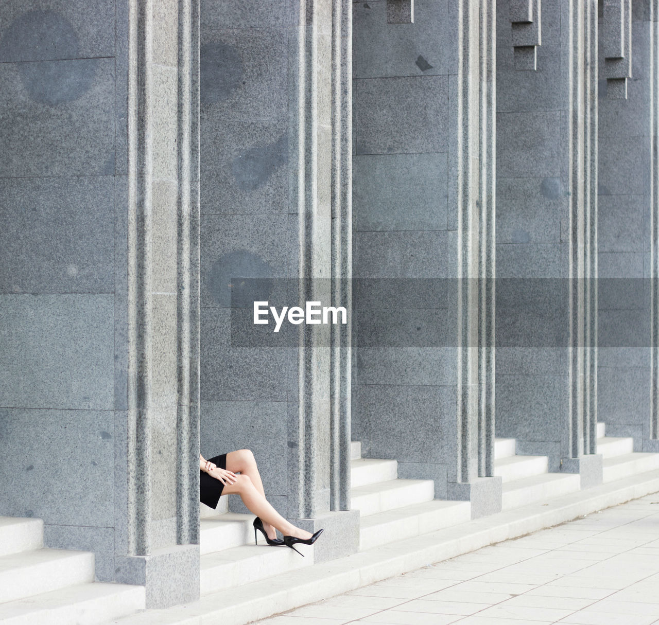 Low section of woman sitting on wall