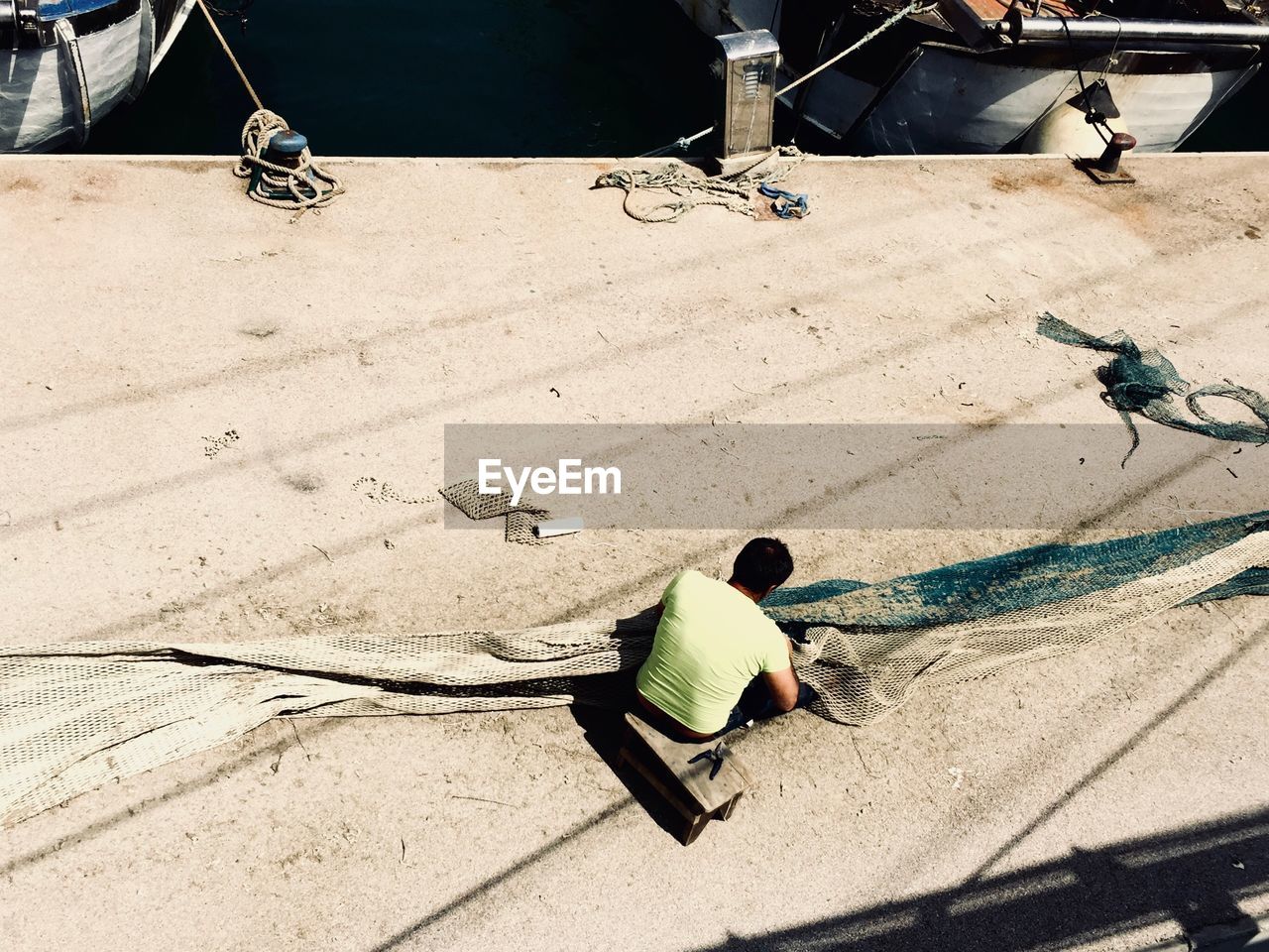 High angle view of working on fishnet at harbor