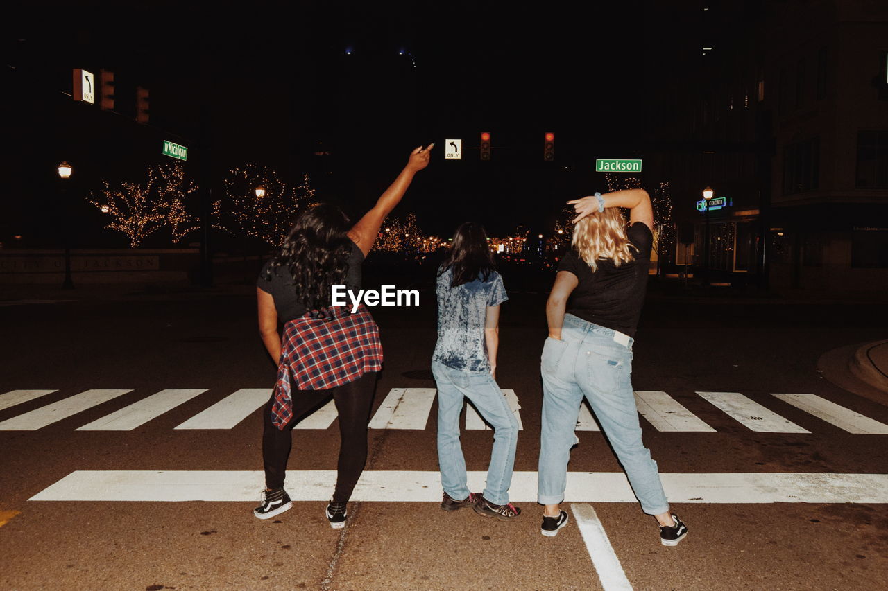 Rear view of people standing on street at night