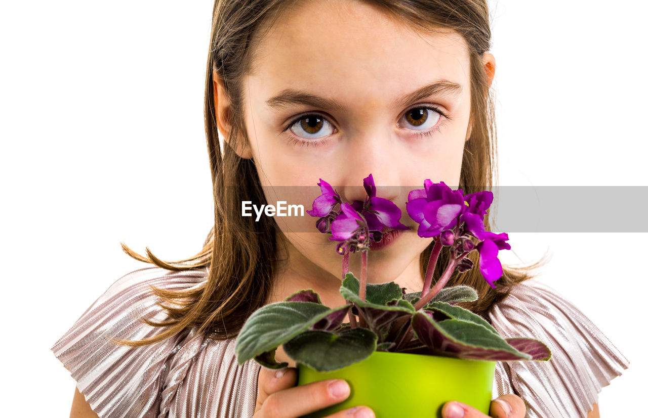 Close-up portrait of girl with flower pot standing against white background