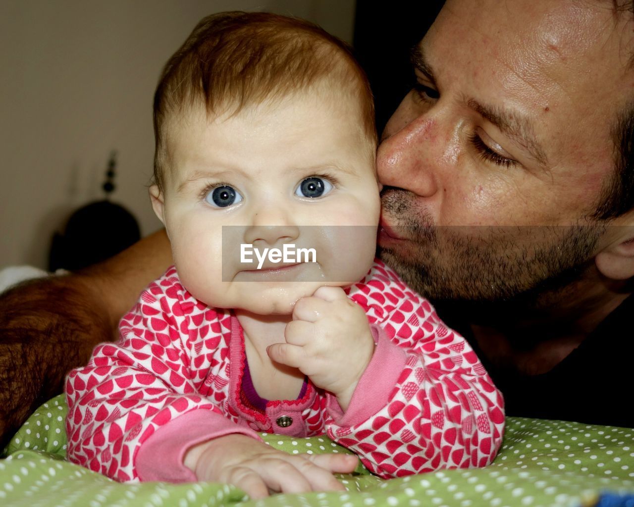 Father kissing cute baby boy on bed