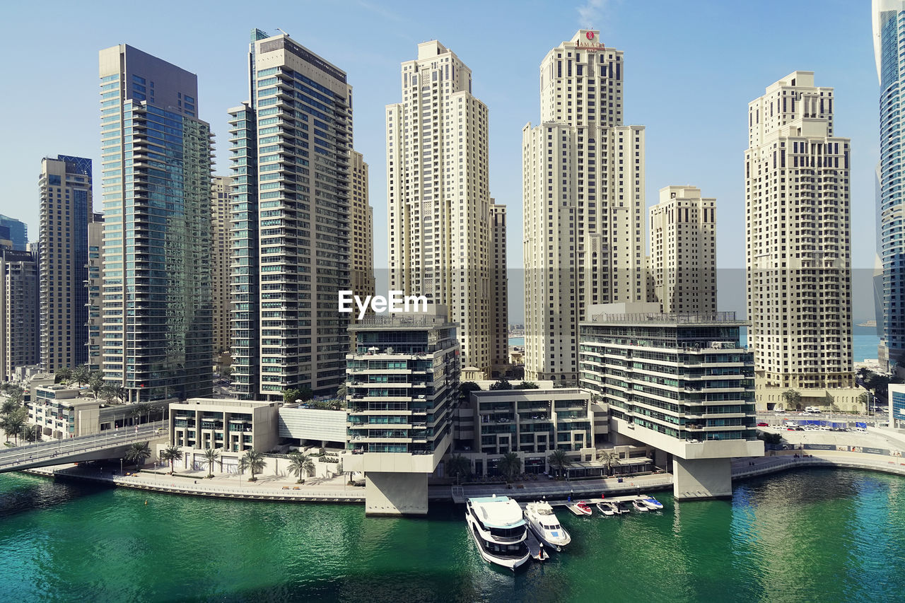 Modern buildings by harbor against sky in city