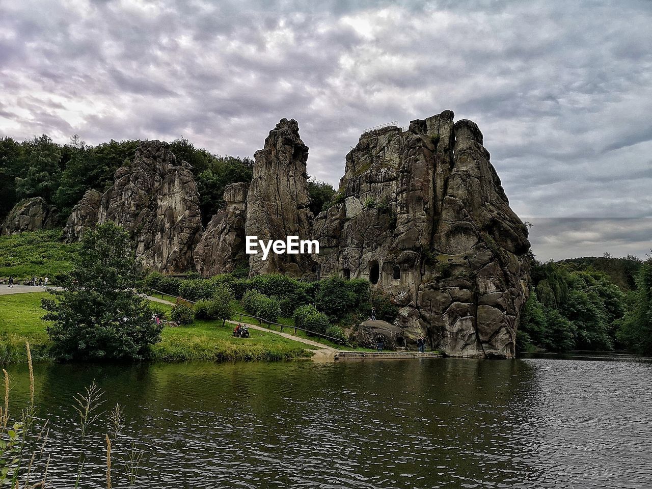 Rock formation by lake against sky