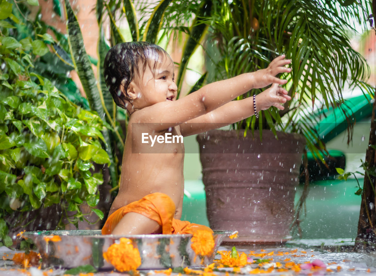 childhood, child, water, one person, men, nature, flower, wet, plant, innocence, fun, day, outdoors, lifestyles, happiness, baby, food and drink, front or back yard, jungle, emotion, toddler, hose, enjoyment, leisure activity, taking a bath, tropical climate, motion, cute, summer, standing, smiling, splashing, bathtub, vacation, washing