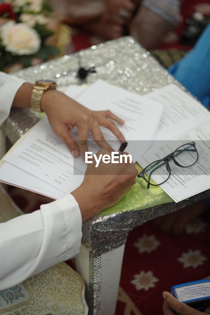 HIGH ANGLE VIEW OF WOMAN HAND HOLDING PAPER