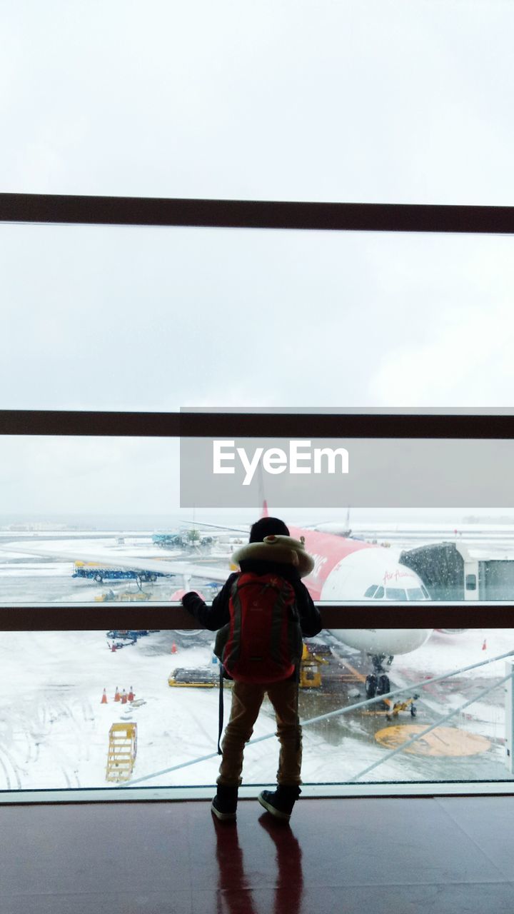 FULL LENGTH REAR VIEW OF MAN STANDING ON AIRPORT