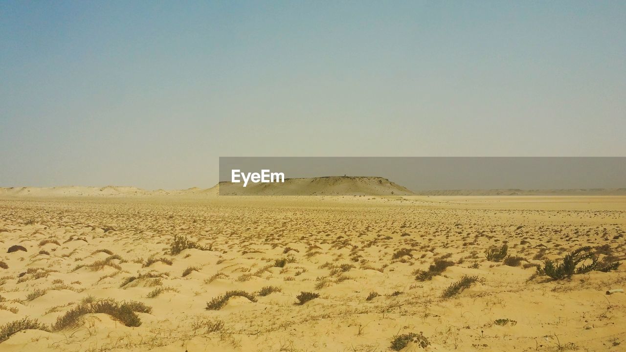 Sand dunes in desert against clear sky
