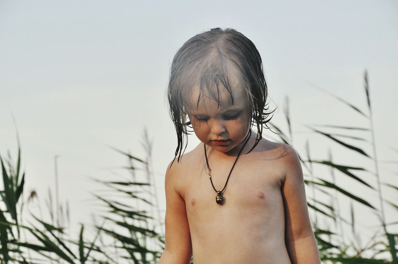 Portrait of shirtless boy against sky