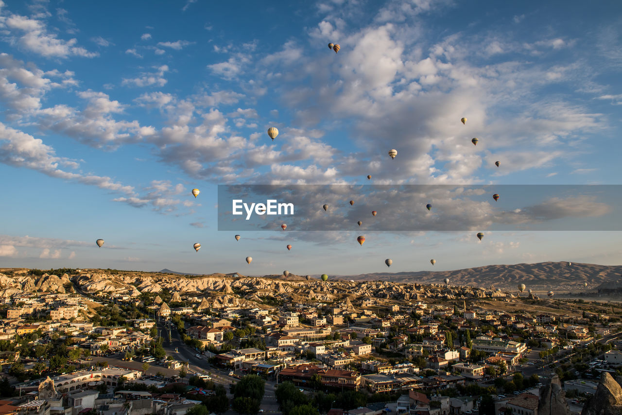 Low angle view of hot air balloons over residential district at cappadocia