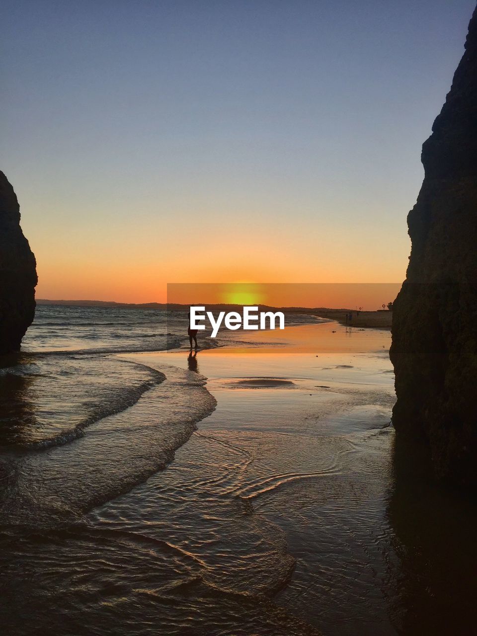 Silhouette people standing on beach against sky during sunset