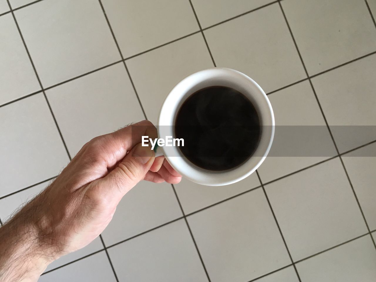 Cropped image of man holding coffee at home