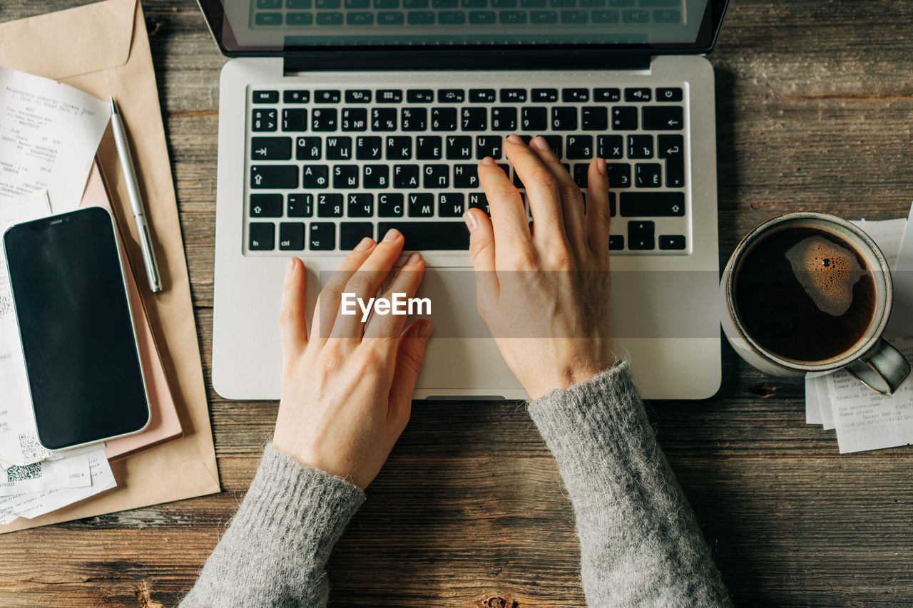 Top view of female hands typing on a laptop keyboard.