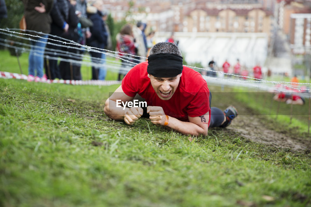 Man shouting and crawling under barbed wires during race