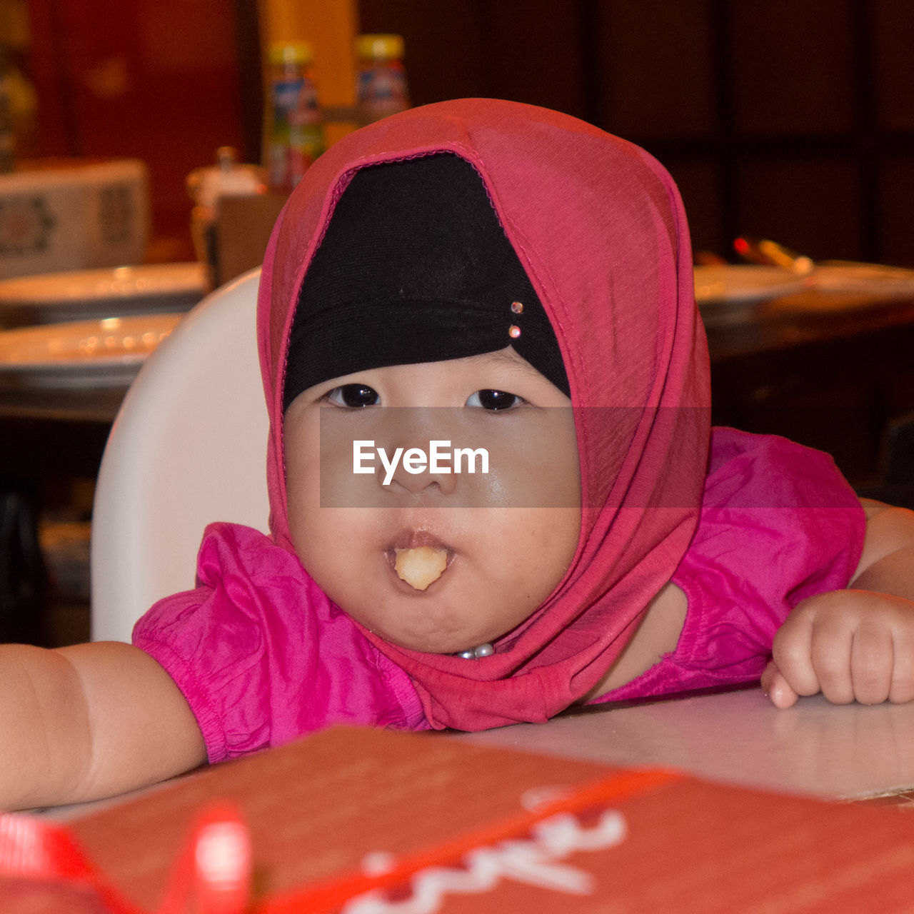 Close-up portrait of cute baby girl eating food in restaurant