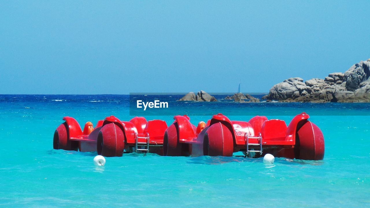 Pedal boats moored in sea